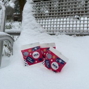 3 petits sachets de bonbons gélifiés avec un message de Noël de l’AKN dans la neige