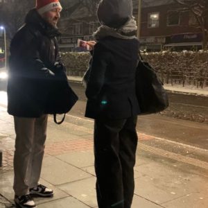 Un promoteur de l’AKN avec un bonnet de Père Noël remet une petite attention à un passager