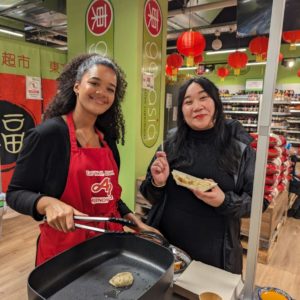 Animatrice qui prépare des produits alimentaires asiatiques sur un stand de dégustation et les remet à une cliente