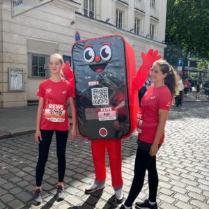 Deux femmes en tenue de course avec la mascotte REWE Appi