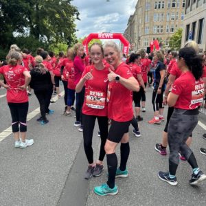 Deux femmes avec le pouce levé au sein d’un groupe de coureuses du REWE Women’s Run à Hambourg