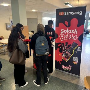 Des étudiants dans un amphithéâtre devant un stand Buldak