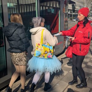 Une promotrice de la Rheinbahn remet un dépliant à deux filles déguisées
