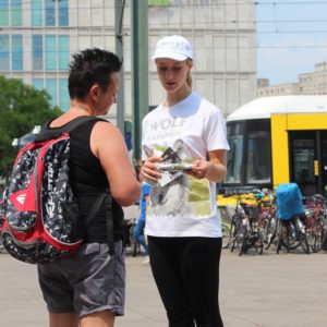 Eine Promoterin von ST-PROMOTIONS verteilt bei einer Samplingaktion in Berlin Produktproben und Flyer an Passanten mit Hund